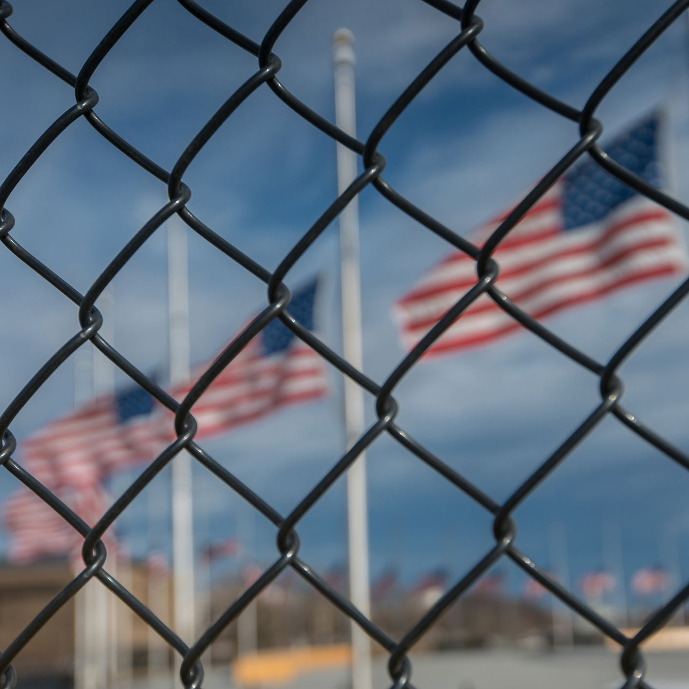 American Flags at Half Mast behind Chain Link Fencing stock photo