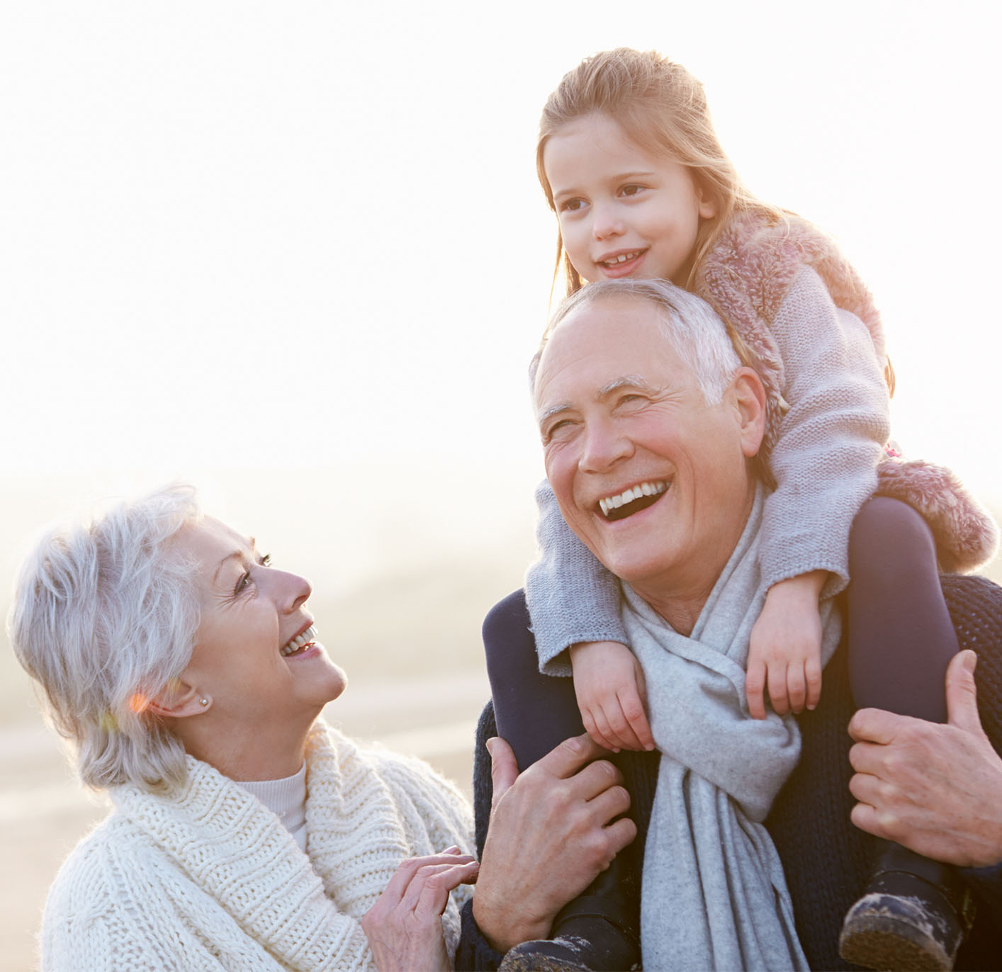 Elderly couple walking on beach with their granddaughter