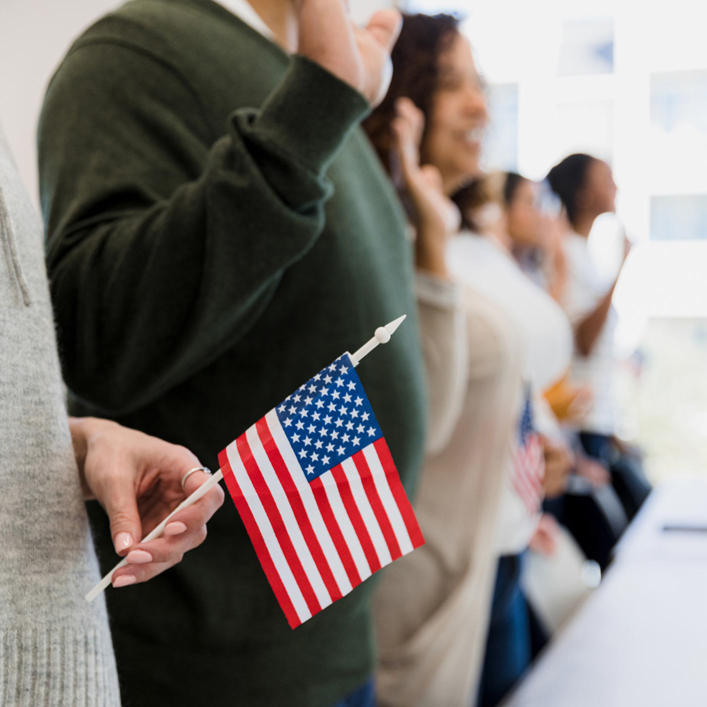 line of people getting sworn in as American Citizens, one is holding a mini American Flag
